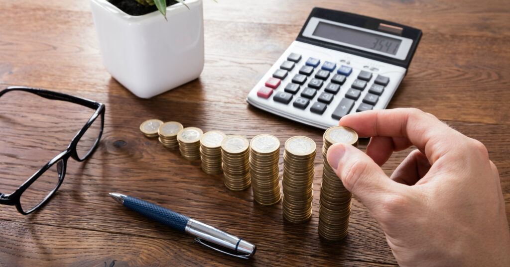 Homem contando moedas junto a uma calculadora e um óculos: ninguém deseja pagar imposto sobre o mesmo item duplamente