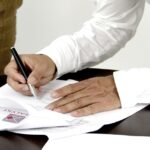 Homem assina documento: veja como fazer a fazer a declaração de saída definitiva do país