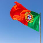 Na imagem destacada contem a bandeira do Portugal nas cores vermelha e verde com o céu de fundo