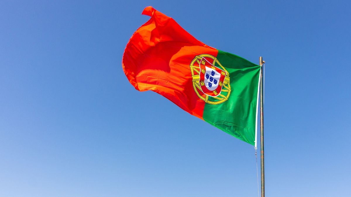 Na imagem destacada contem a bandeira do Portugal nas cores vermelha e verde com o céu de fundo