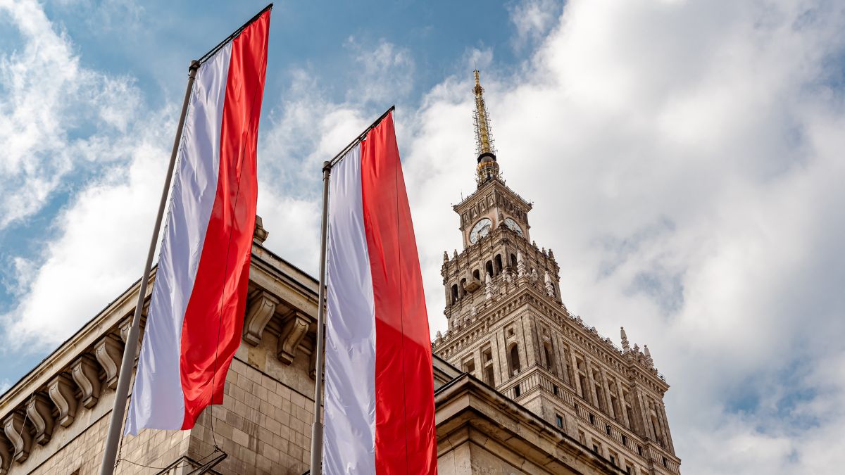 Na imagem destacada contem duas bandeiras da polonia e de fundo temos um palacio